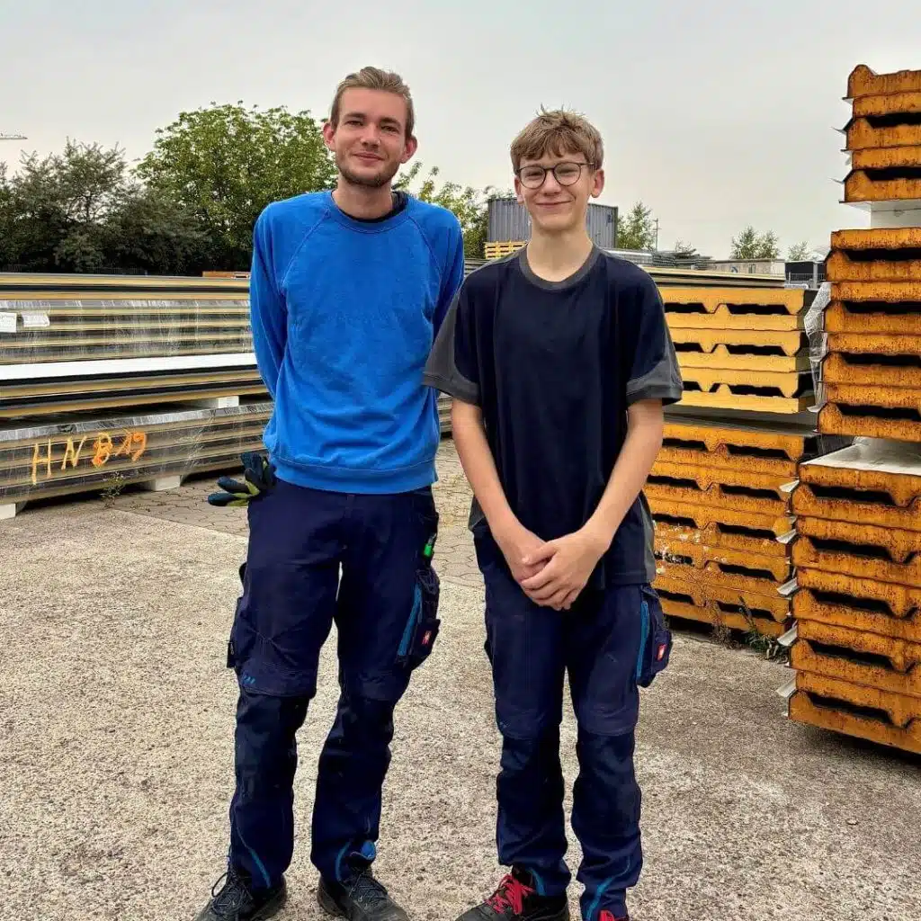 Praktikant Luis mit Lagermitarbeiter Elias draußen vor Sandwichpaneelen